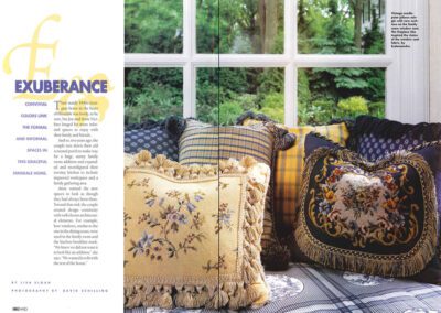 A cozy window seat with multiple decorative pillows, each adorned with floral and plaid designs, sits against a large window overlooking a lush green garden. The text beside the image discusses vibrant home décor ideas, emphasizing color and pattern inspirations.