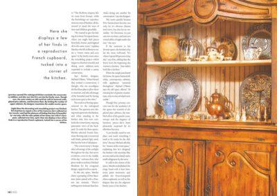 A rustic wooden cupboard with ornate carvings is displayed. The cupboard features two shelves: the top shelf holds a vase, assorted ceramic items, and a couple of pitchers, while the bottom shelf showcases various brass and silver objects, including teapots and trays.